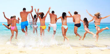 Groups of friends running into the blue ocean on a sunny day